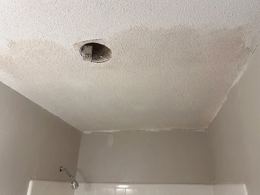 Textured ceiling with damage around a light fixture, before repair
